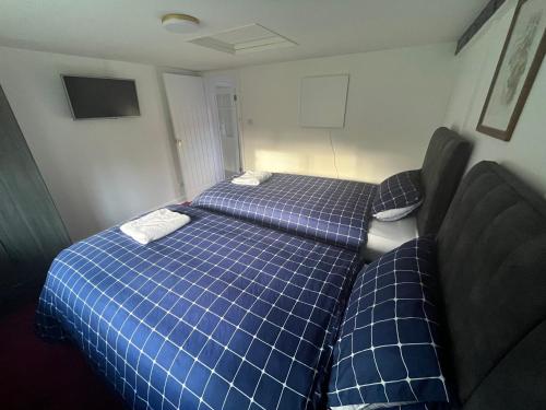 two beds in a small room with blue at Yu’s Guest House in Sevenoaks