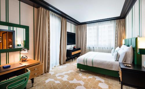 a hotel room with a bed and a desk and a television at Dinamo Hotel Baku in Baku