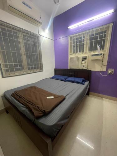 HOME STAY in ground floor في تشيناي: سرير في غرفة مع جدران أرجوانية ونوافذ