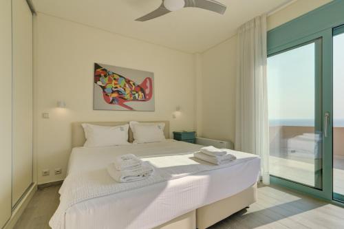 a bedroom with a large white bed with towels on it at Ouzo Panoramic Houses 2, with private pool in Plomarion