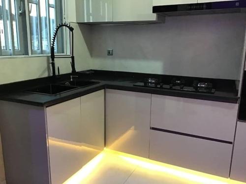 a kitchen with white cabinets and a sink with a light at Brandison Apartments in Rumodome