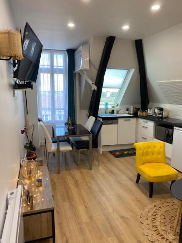 a kitchen and living room with a table and a yellow chair at Cosy & Tendance Spa in Poitiers