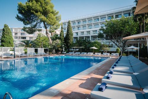 una piscina con tumbonas y un edificio en THB Los Molinos Adults Only, en Ibiza