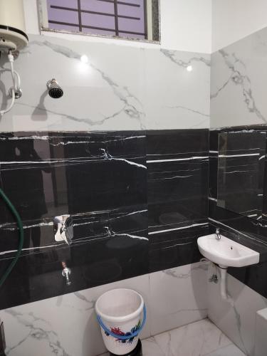 a black and white bathroom with a sink and a toilet at Shiv Shakti Homestay in Ujjain