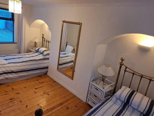 a bedroom with two beds and a mirror at Saltwater Cottage in Dunseverick