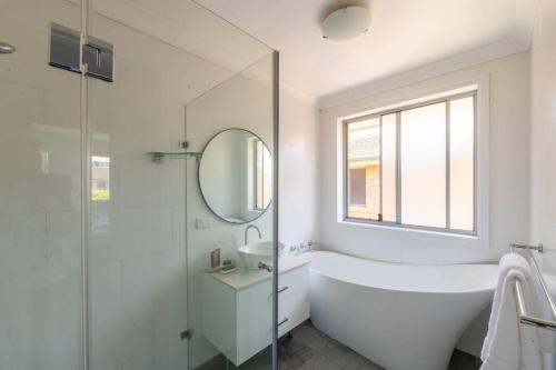 a bathroom with a tub and a sink and a mirror at The Spotted Gum Northern Beaches in Warriewood