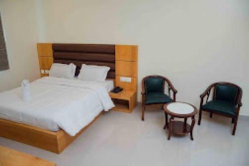 una camera con un letto e due sedie e un tavolo di Hotel Grand Lotus Dimapur a Dimāpur