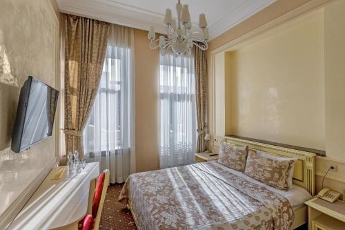 a hotel room with a bed and a television at Vintage Art Hotel in Odesa