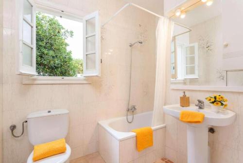 a bathroom with a toilet and a sink and a window at Villa Mar Azul in Arenal d'en Castell