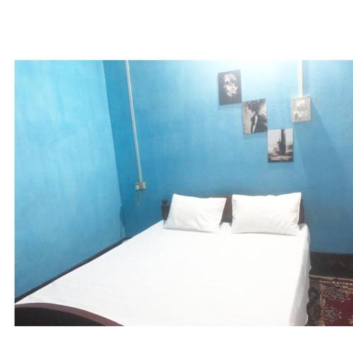 a bedroom with a large white bed with a blue wall at Serenity Home in Nowgong