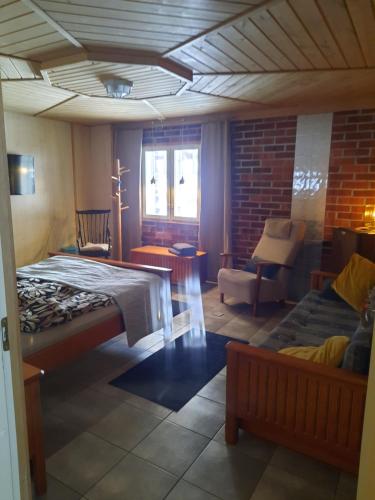 ein Schlafzimmer mit einem Bett, einem Sofa und einem Stuhl in der Unterkunft Sininen Hetki Bed& Breakfast majoitus meren äärellä in Kaskö