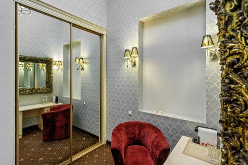 a bathroom with a red chair and a mirror at Vintage Art Hotel in Odesa