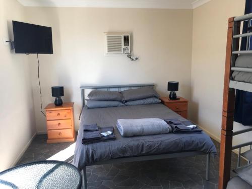 Un dormitorio con una cama con TV y un colchón reforzado en Australian Hotel Winton Cabins, en Winton