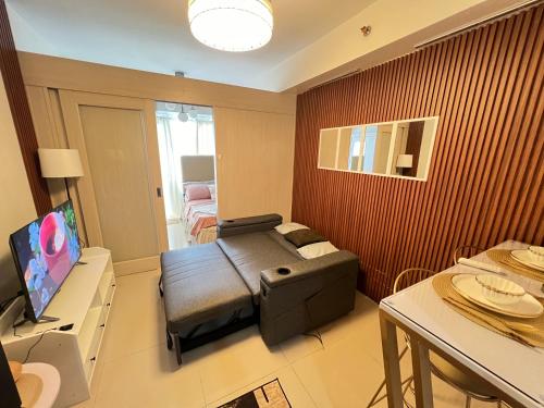 a small living room with a couch and a television at Sea Residences: Eyal’s Suite Condotel near MOA/Mall of Asia in Manila