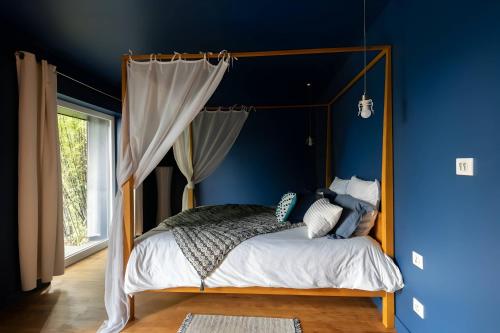 勒芒的住宿－Villa Isaac - Luxueuse - Parking - 16p - Rêve au Mans，一间卧室配有一张天蓬床和蓝色的墙壁