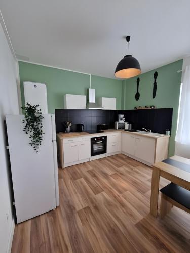 une cuisine avec des armoires blanches et des murs verts dans l'établissement Le Lotus - Centre - 4pers - Rêve au Mans, au Mans