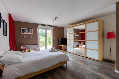 ein Schlafzimmer mit einem großen Bett und einer Glasschiebetür in der Unterkunft Le Bois D'Ourné - Nature - Piscine - 7p - Rêve au Mans in Guécélard