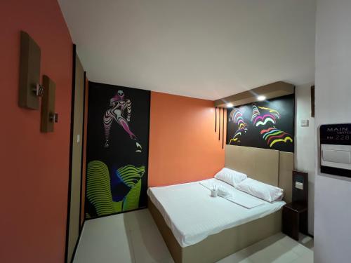 a small room with a bed and paintings on the wall at Quinn Dormittelle in Manila