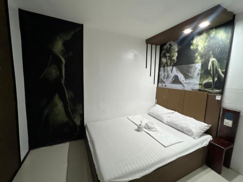 a room with a white bed with a painting on the wall at Quinn Dormittelle in Manila