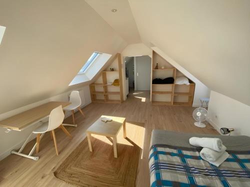 Cette chambre mansardée comprend un lit, un bureau et une table. dans l'établissement L'incroyable - Centre - 4pers - Rêve au Mans, au Mans
