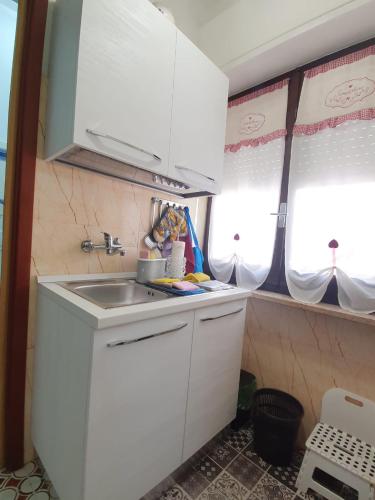 a small kitchen with white cabinets and a sink at LA CASA DEI PARGOLI JUNIOR in Matera