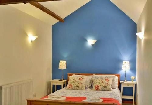 a bedroom with a blue wall and a bed with pillows at Finest Retreats - Little Dunley - Acorn Cottage in Bovey Tracey
