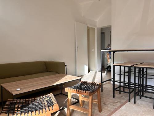 uma sala de estar com um sofá, uma mesa e um banco em Appartement 4 lits • Tout neuf em Montreuil