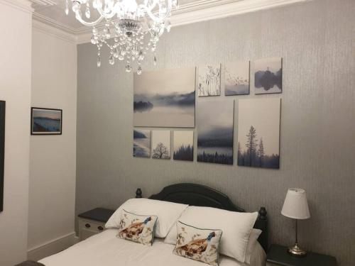 een slaapkamer met een bed met een kroonluchter en foto's aan de muur bij Stylish ground floor 2 bedroomed apartment. in Barrow in Furness