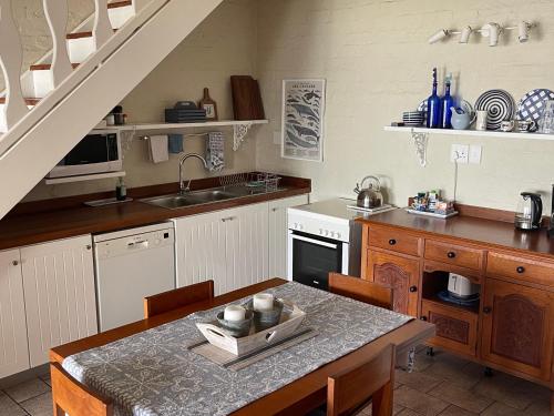 a kitchen with a sink and a table with chairs at By Die See in Gordonʼs Bay