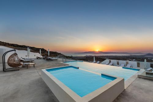 a pool on the roof of a house with the sunset at Mandilaras Village in Vívlos