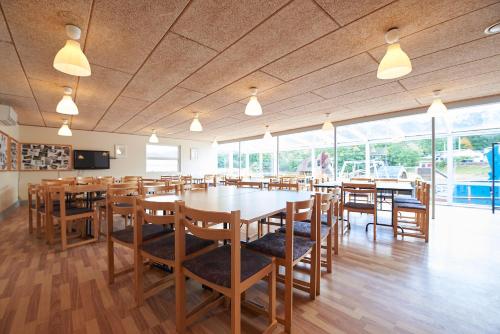 a restaurant with wooden tables and chairs and windows at Randbøldal Camping & Cabins in Randbøl