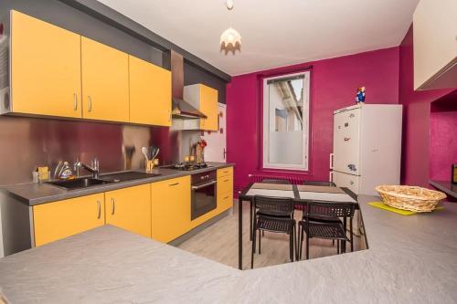 une cuisine avec des murs jaunes et violets et une table dans l'établissement 3 chambres spacieuses - 2 min à pied gare, à Bourg-en-Bresse