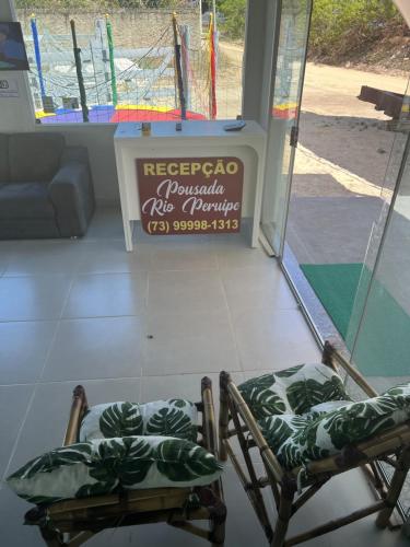 two chairs in front of a store with a sign at POUSADA RIO PERUYPE in Nova Viçosa