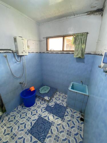 bagno piastrellato blu con servizi igienici e finestra. di Villa Sunda Ciwidey a Nempel