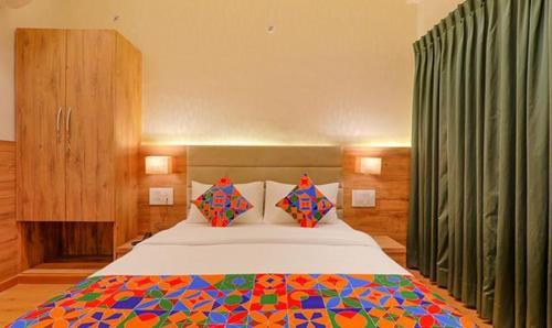 een slaapkamer met een groot bed en een kleurrijke deken bij FabHotel Pratham Inn in Chinhat
