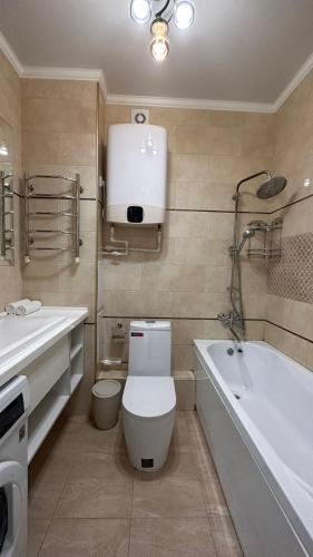 a bathroom with a toilet and a bath tub at Luxe Apartments on Stepnoy in Karagandy