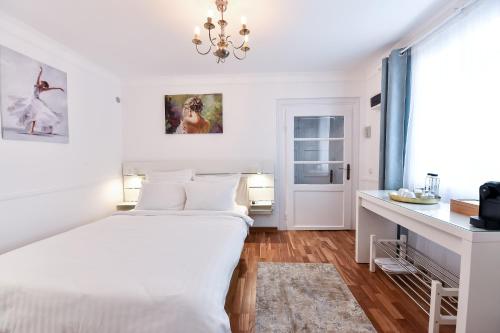 a white bedroom with a bed and a desk at FIVE ROOMS in Braşov