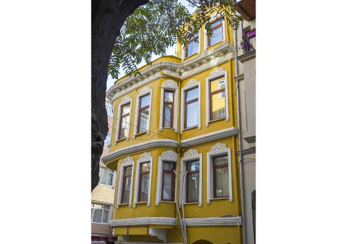 un edificio amarillo con ventanas blancas junto a un árbol en Mar Suite en Estambul