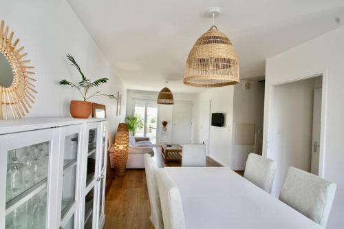 una sala de estar blanca con mesa blanca y sillas en Charmante maison avec piscine en Puilboreau