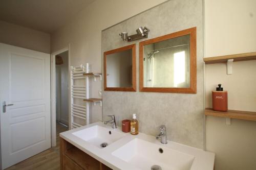 La salle de bains est pourvue d'un lavabo blanc et d'un miroir. dans l'établissement Charmante maison avec piscine, à Puilboreau