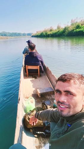 a man sitting in a boat on the water at Hotel Butterfly - Peaceful Garden for Nature Lovers in Sauraha