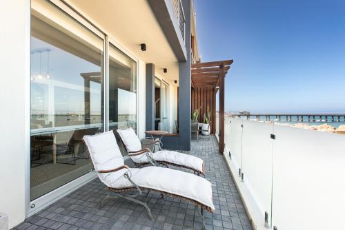 a balcony with white chairs and a view of the ocean at The Pearls Swakopmund in Swakopmund
