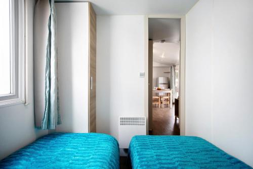 two beds in a small room with blue sheets at Bungalow T3 I I -15 Min From Nazaré in Pataias