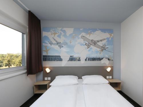 a bedroom with two beds and a map of the world at B&B Hotel Berlin-Airport in Schönefeld