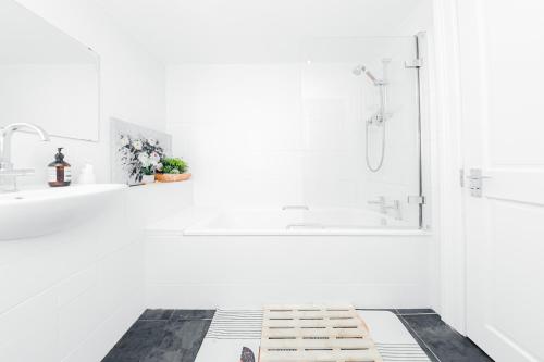a white bathroom with a shower and a bathtub at Double room w/Projector & Garden Hot Tub in London