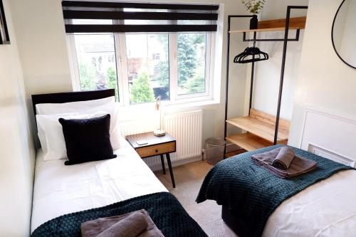 a bedroom with two beds and a window at 7 Persons Comfortable Guest House in Watford