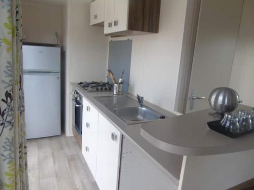 une cuisine avec un évier et un réfrigérateur dans l'établissement Mobil home 685 3 chambres Siblu La Réserve, à Gastes