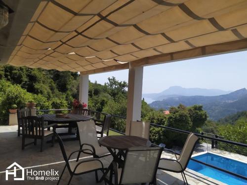 a patio with tables and chairs and a view of the mountains at Villa VERA - private villa for 8 guests with pool in Kymi