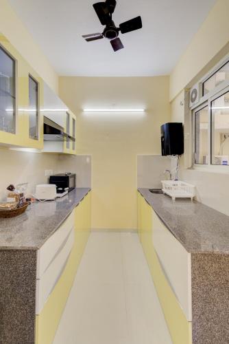 a kitchen with white counters and a ceiling fan at Luxe 2BHK 10min from GOI airport with Pool access in Dabolim
