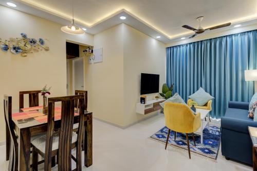 a living room with a table and a blue couch at Luxe 2BHK 10min from GOI airport with Pool access in Dabolim